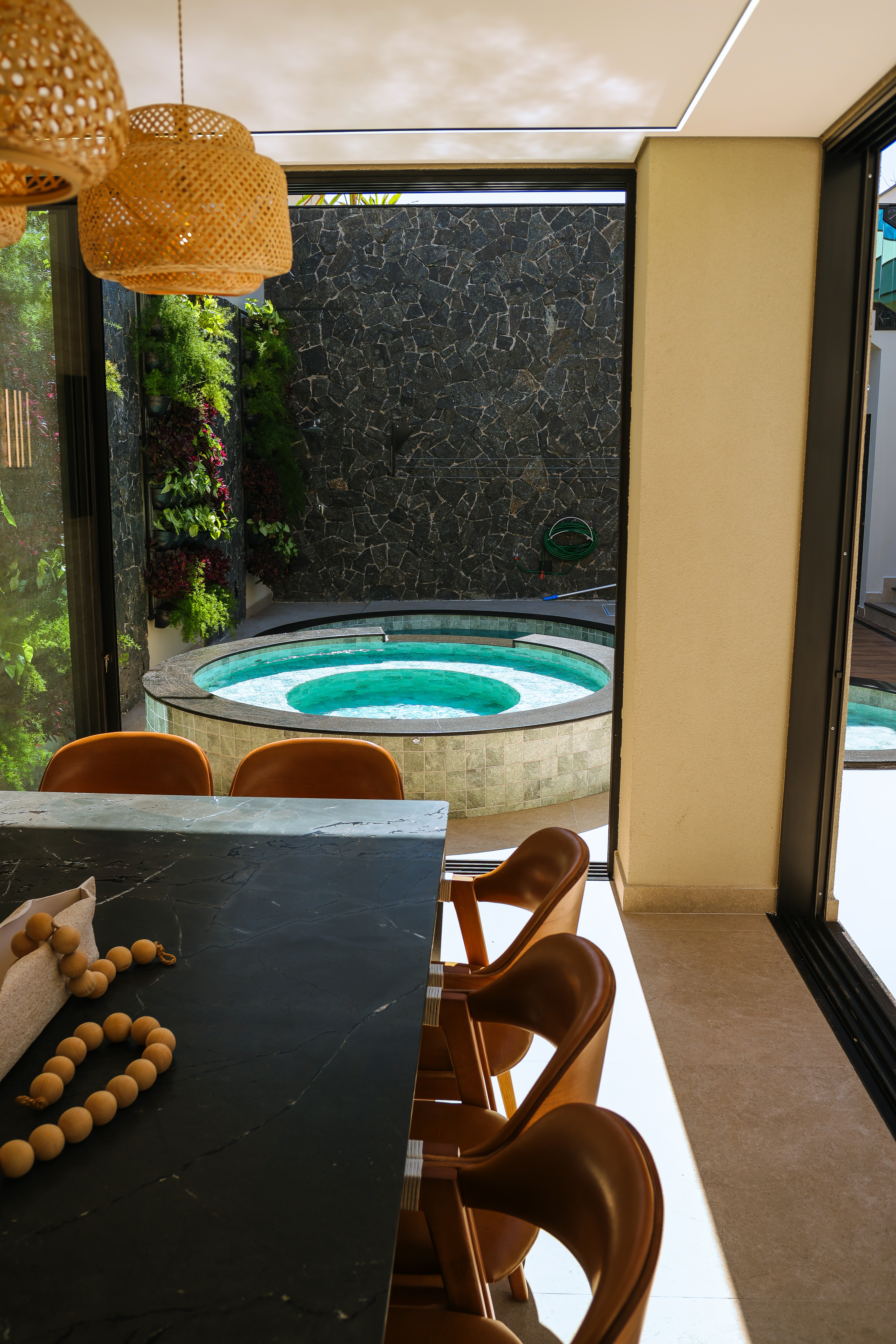 Mesa e spa redondo com jardim vertical ao fundo