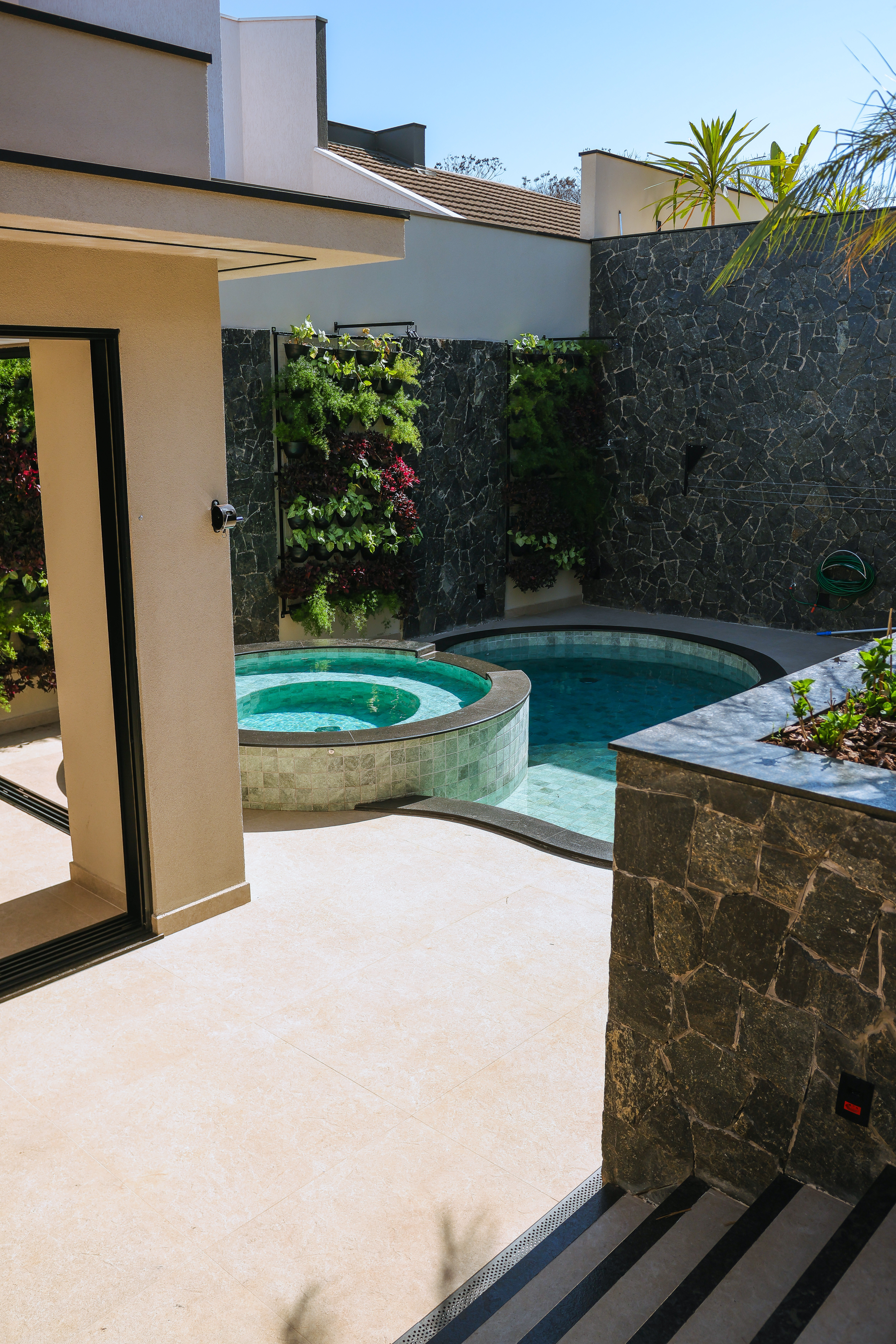 Piscina e spa com parede de pedra e jardim vertical